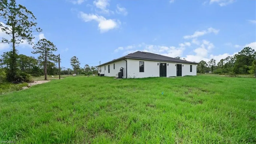 Back of house featuring stucco siding and a lawn