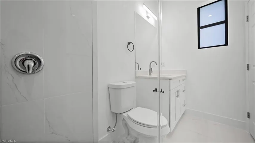 Full bath with vanity, a shower, and marble look tiles