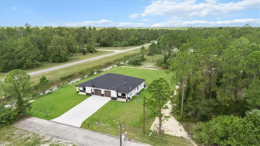 Aerial view of property and surrounding area with a heavily wooded area