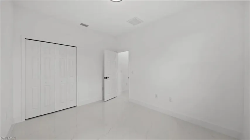 Unfurnished bedroom with marble look tile flooring and a closet