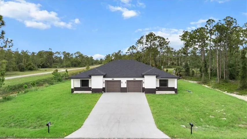 View of front of house featuring a front lawn, a garage, stucco siding, driveway, and a shingled roof