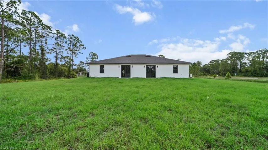 Rear view of house with a lawn and stucco siding