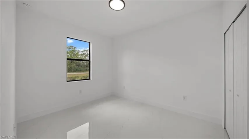 Unfurnished bedroom featuring light marble finish flooring and a closet