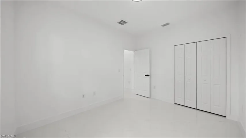 Unfurnished bedroom with marble finish floors and a closet