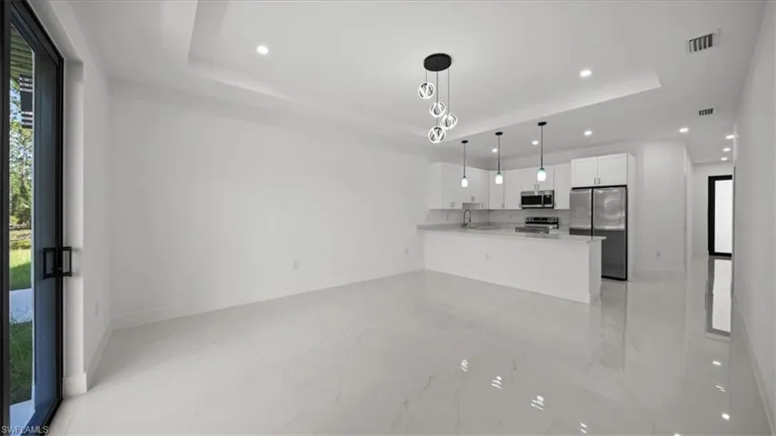 Kitchen featuring a tray ceiling, stainless steel appliances, white cabinetry, recessed lighting, and light countertops