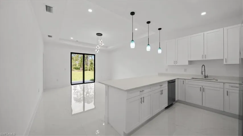 Kitchen featuring light marble finish flooring, a peninsula, white cabinets, and recessed lighting