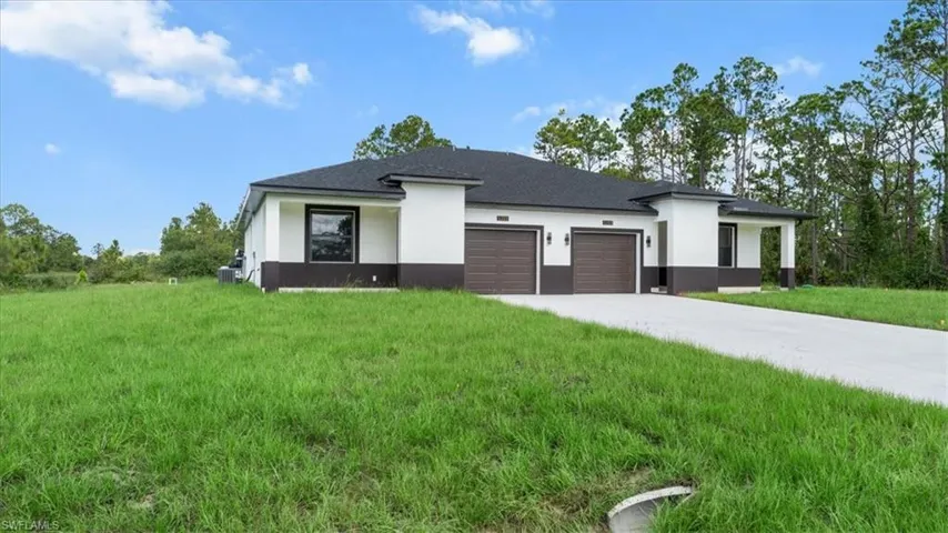 View of front of house with a garage, stucco siding, concrete driveway, and a front yard