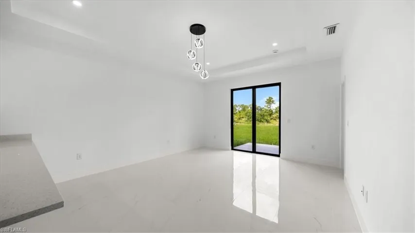 Empty room with a raised ceiling, marble look tile flooring, and recessed lighting