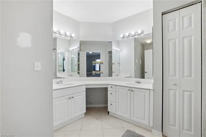 Bathroom with a closet, double vanity, and light tile patterned floors