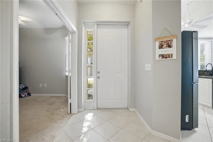 Entryway featuring ceiling fan, light tile patterned floors, and light colored carpet