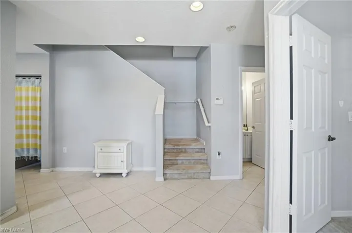 Staircase with tile patterned flooring and recessed lighting