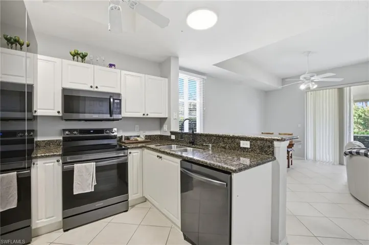 Kitchen featuring a ceiling fan, stainless steel appliances, dark stone counters, a peninsula, and white cabinets