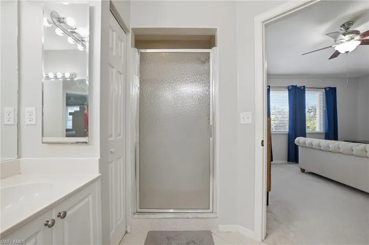 Bathroom with a ceiling fan, a shower stall, connected bathroom, vanity, and light tile patterned flooring