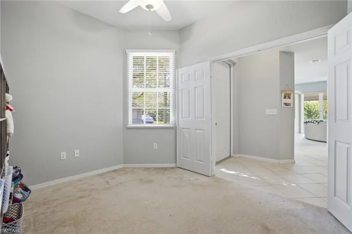 Unfurnished bedroom featuring light carpet, multiple windows, a ceiling fan, and light tile patterned floors