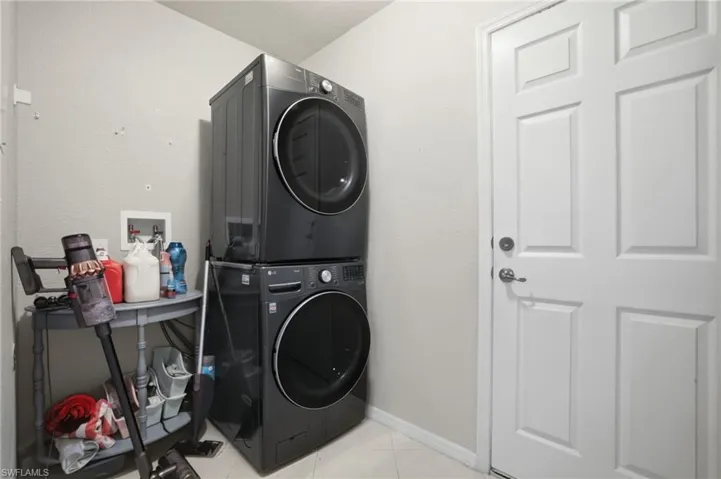 Laundry area featuring stacked washer / dryer and light tile patterned floors