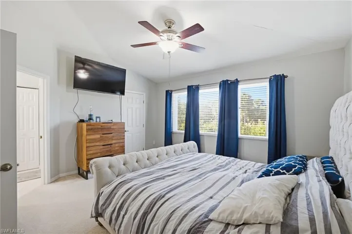 Carpeted bedroom featuring vaulted ceiling and a ceiling fan