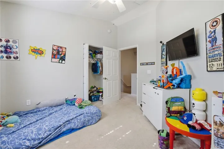 Bedroom featuring light colored carpet, lofted ceiling, and ceiling fan