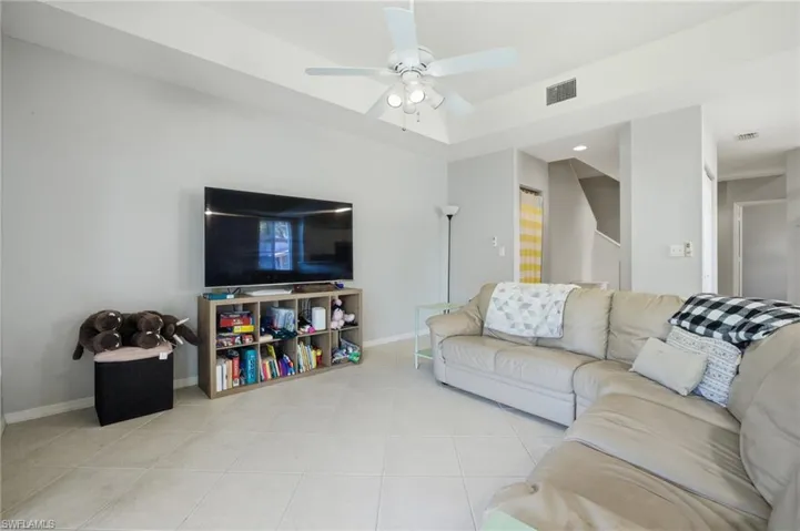 Living area featuring light tile patterned floors and a ceiling fan