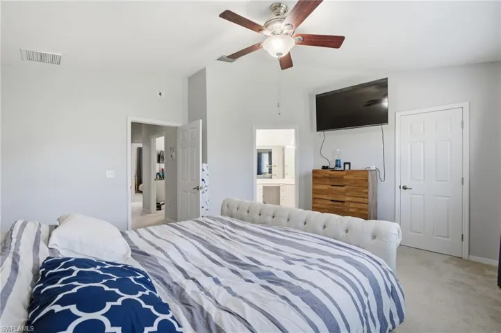 Bedroom featuring lofted ceiling, light carpet, a ceiling fan, and ensuite bathroom