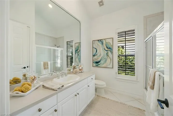 Full bath featuring vanity, light tile patterned flooring, and enclosed tub / shower combo