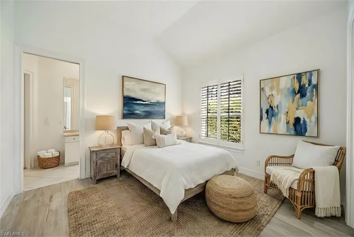 Bedroom featuring light wood-type flooring, lofted ceiling, and ensuite bathroom