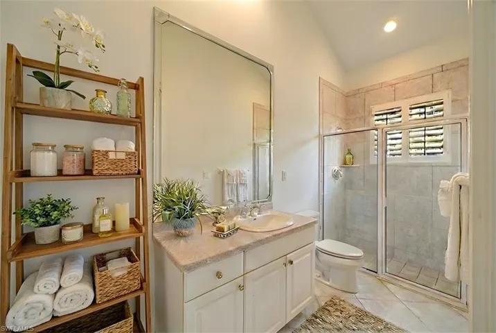 Bathroom featuring vanity, a shower stall, lofted ceiling, light tile patterned floors, and recessed lighting
