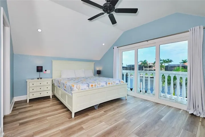 Bedroom with lofted ceiling, access to exterior, light wood-style floors, recessed lighting, and ceiling fan