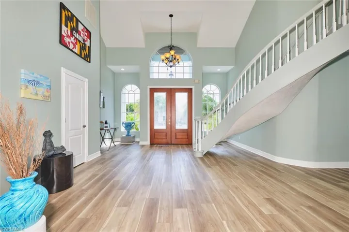 Entrance foyer with a chandelier, light wood-style flooring, a high ceiling, and stairs