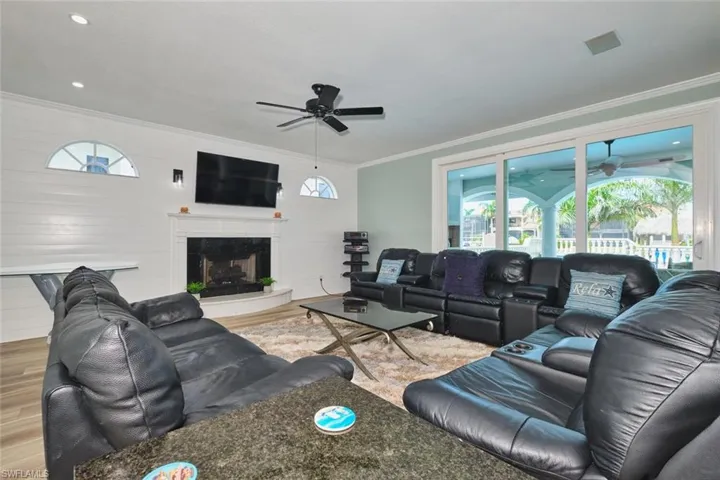 Living room with a ceiling fan, healthy amount of natural light, ornamental molding, wood finished floors, and a premium fireplace