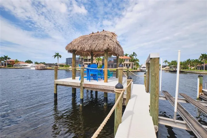 Dock featuring boat lift, a water view, and a residential view