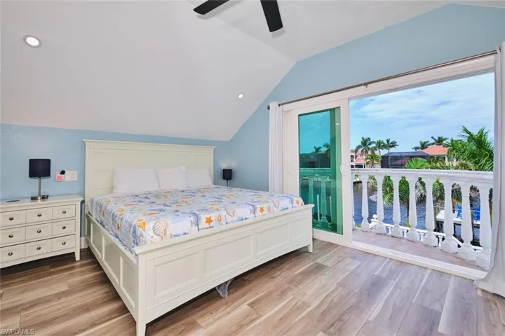 Bedroom featuring lofted ceiling, access to exterior, light wood-style flooring, recessed lighting, and a ceiling fan