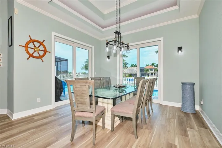 Dining room featuring a tray ceiling, light wood-style floors, and ornamental molding
