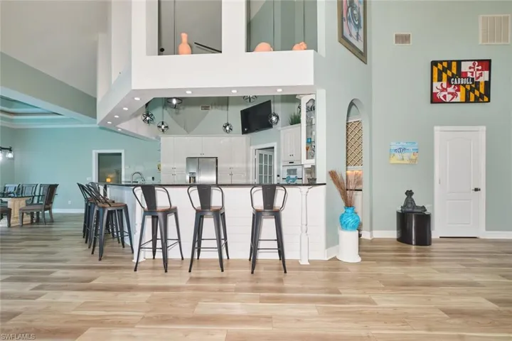 Kitchen with white cabinetry, a breakfast bar area, stainless steel fridge with ice dispenser, light wood-style floors, and a peninsula