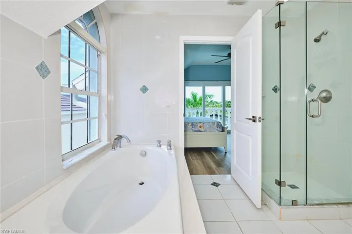 Ensuite bathroom with a bath, tile walls, tile patterned flooring, and a stall shower