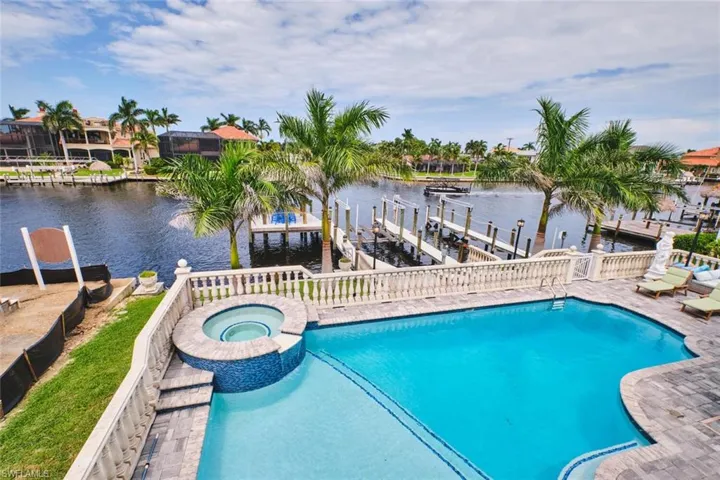 View of swimming pool with a water view, boat lift, a pool with connected hot tub, a boat dock, and a patio