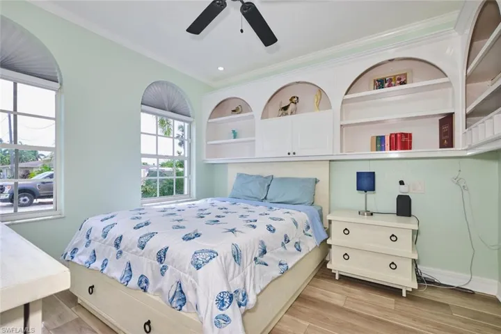 Bedroom featuring light wood-style flooring, ceiling fan, and crown molding