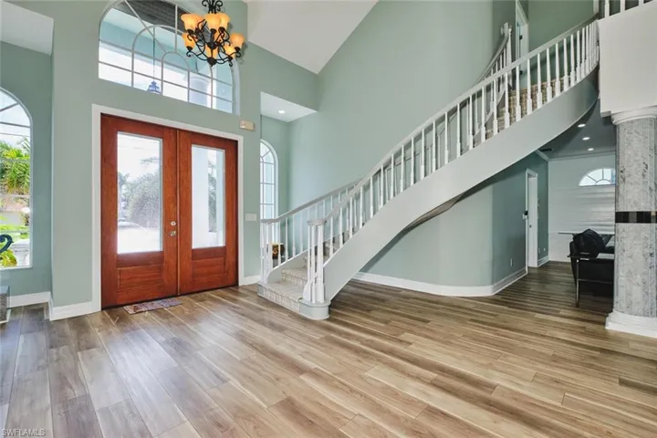 Entryway featuring french doors, stairs, a high ceiling, wood finished floors, and a chandelier