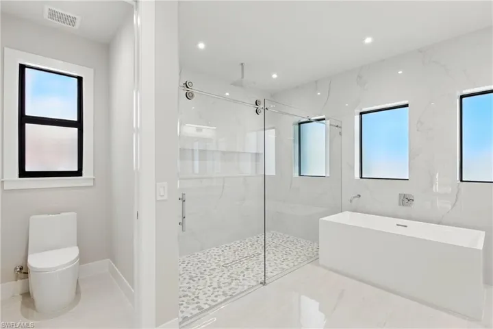 Master bath, huge shower with multiple shower heads, deep tub, modern one piece toilet