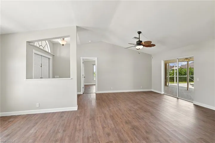 Vaulted ceilings with a neutral color palette, wood-finish flooring, ceiling fan, and sliding glass doors