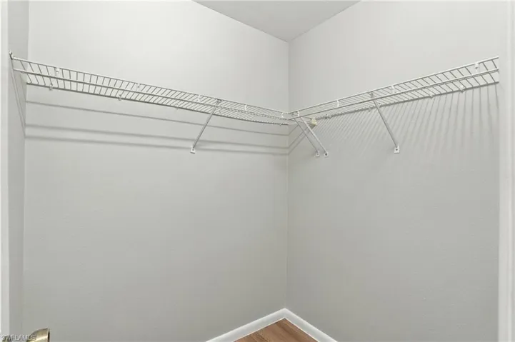 Walk-in storage space featuring neutral wall paint, wood-finish flooring, and white wire shelving