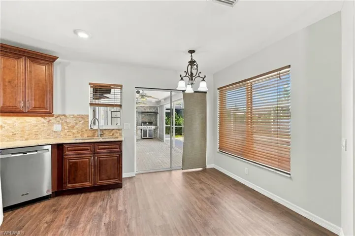 Kitchen area featuring wood-finish cabinetry, stone-tiled backsplash, recessed lighting, wood-finish flooring, and sliding glass doors