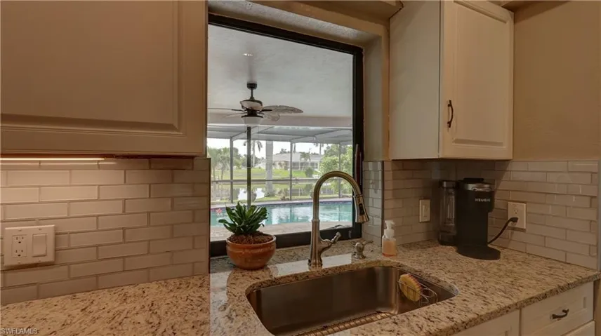 Kitchen sink featuring a gooseneck faucet, granite countertops, and a subway tile backsplash