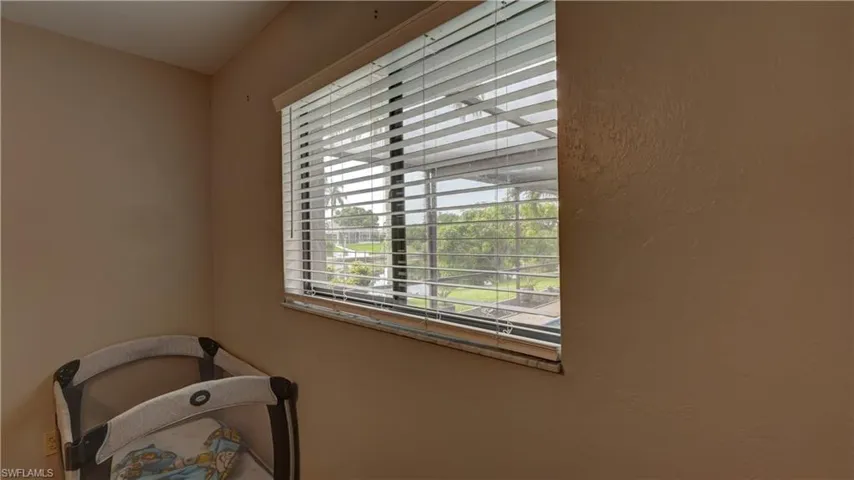 Interior room featuring a single window with horizontal blinds, offering a partial exterior view