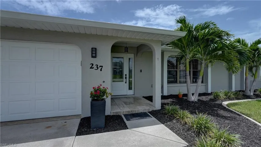 Stucco exterior featuring a two-car garage, double-door entry, and a covered entryway