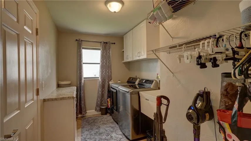 Dedicated laundry room featuring built-in cabinetry, wire shelving, and a window for natural light