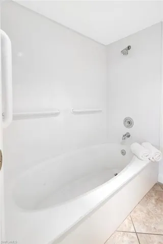 Full bath with tile patterned floors and shower / bath combination