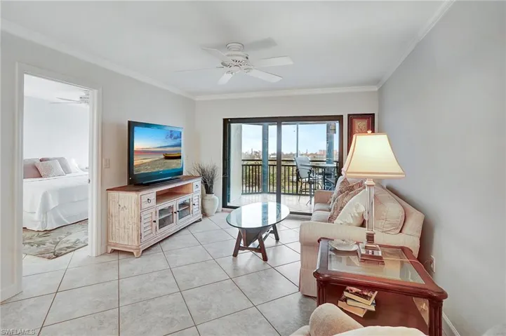 Living room with ornamental molding, light tile patterned floors, and a ceiling fan