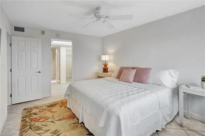 Bedroom featuring light tile patterned flooring, ensuite bath, and ceiling fan
