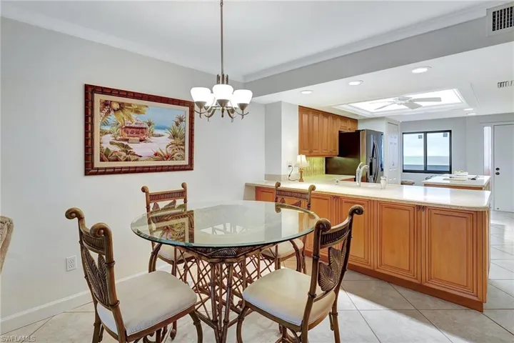 Dining area with light tile patterned floors, crown molding, recessed lighting, a chandelier, and a tray ceiling