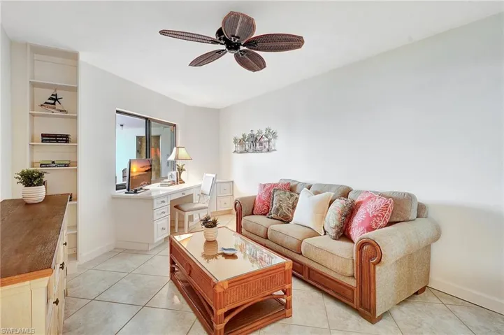 Living area featuring light tile patterned flooring, an office area, a ceiling fan, and built in shelves
